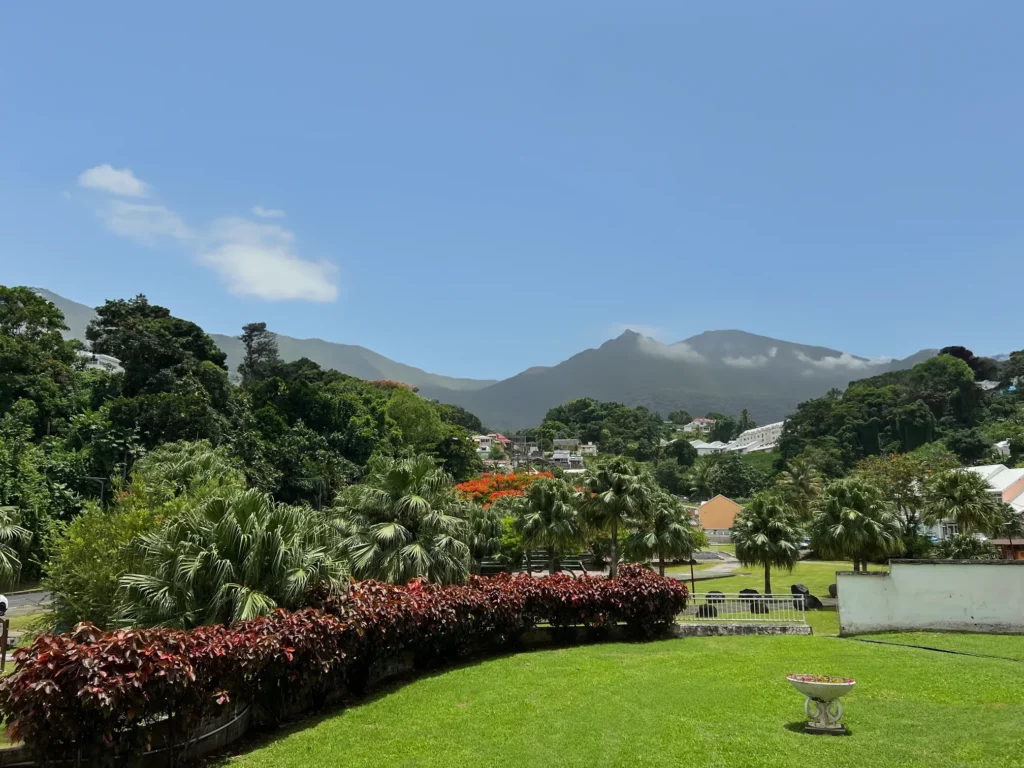 Vue panoramique sur un parc verdoyant et des montagnes tropicales.