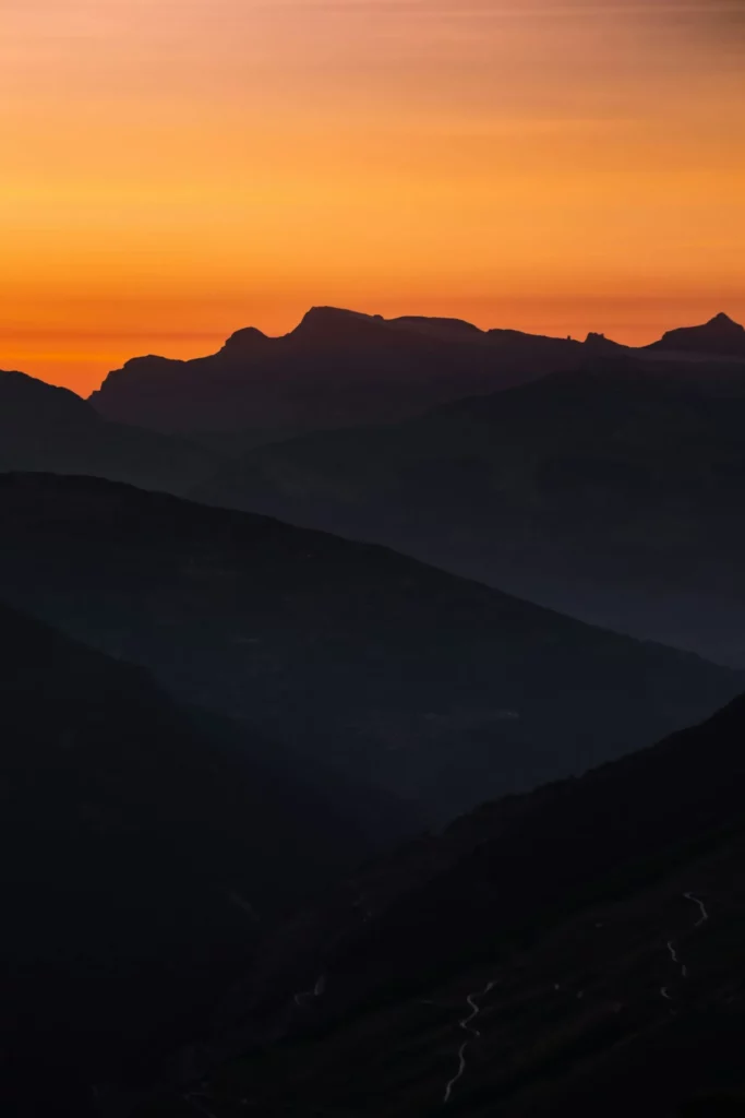 Paysage de montagnes au coucher du soleil sous un ciel orange.